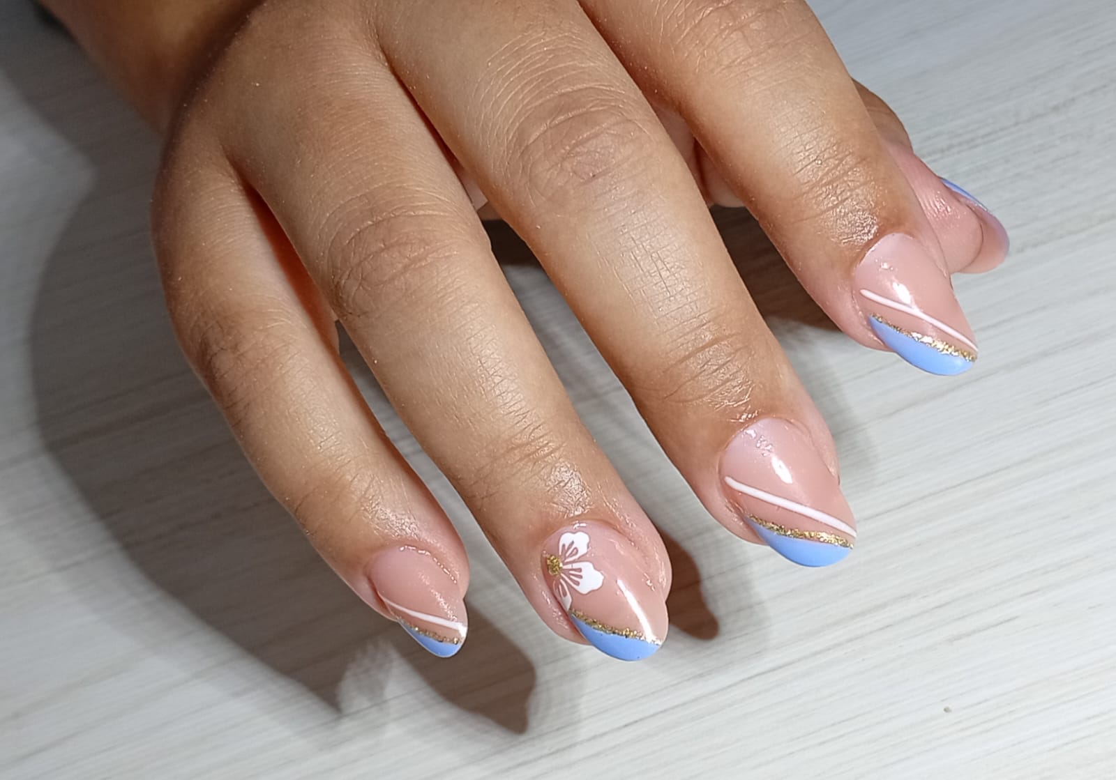 Nail art delicada com azul, nude e flor branca